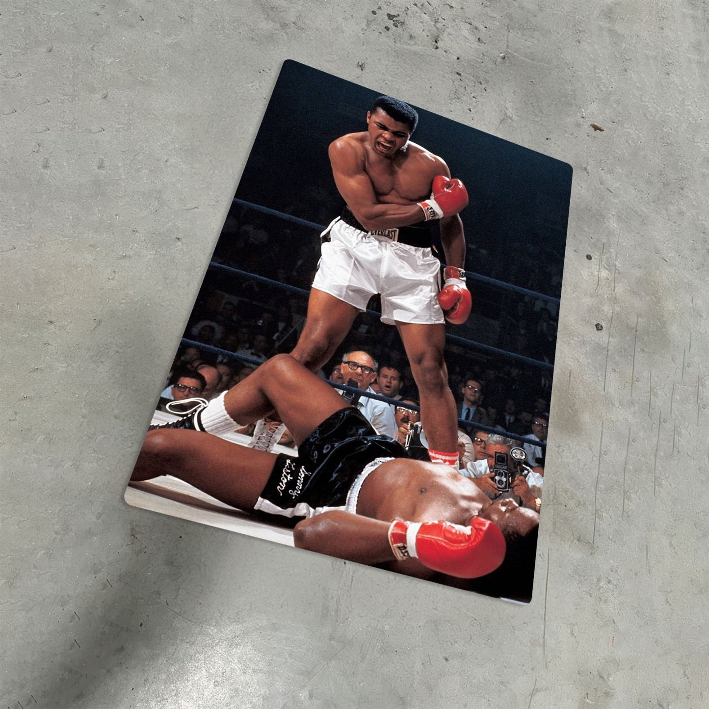 Muhammad Ali vs Sonny Liston iconic knockout boxing photo printed on a durable metal poster resting on a concrete floor.