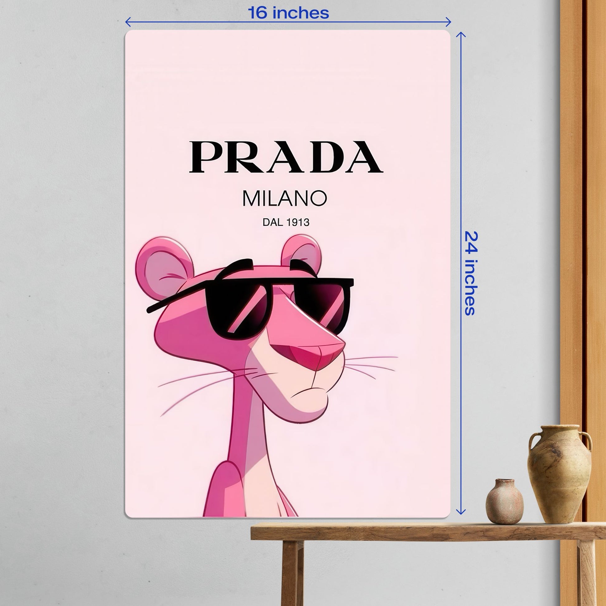 Large size Pink Panther Prada luxury fashion metal poster measuring 16 inches by 24 inches displayed on a white wall above a wooden table.
