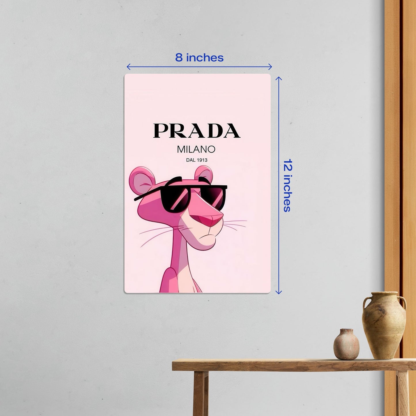Small size Pink Panther Prada luxury fashion metal poster measuring 8 inches by 12 inches shown as wall decor above a wooden console table.