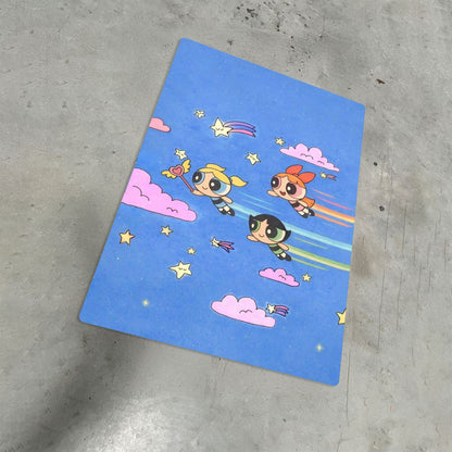 Powerpuff Girls metal poster artwork featuring Blossom, Bubbles, and Buttercup flying in a blue starry sky with pink clouds.