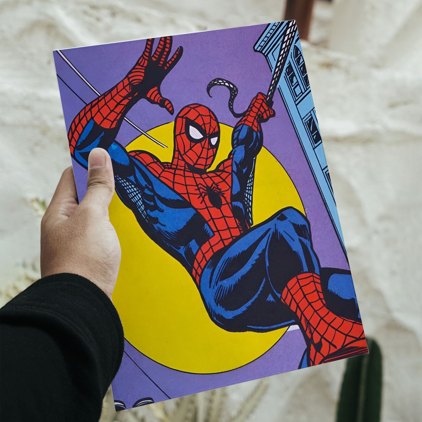 Close-up of a hand holding the printed Spiderman Classic Comic Swing Poster, displaying the high-quality print and vibrant retro colors of the superhero wall art.