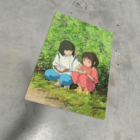 Spirited Away Chihiro and Haku anime metal poster art lying on a grey concrete floor.