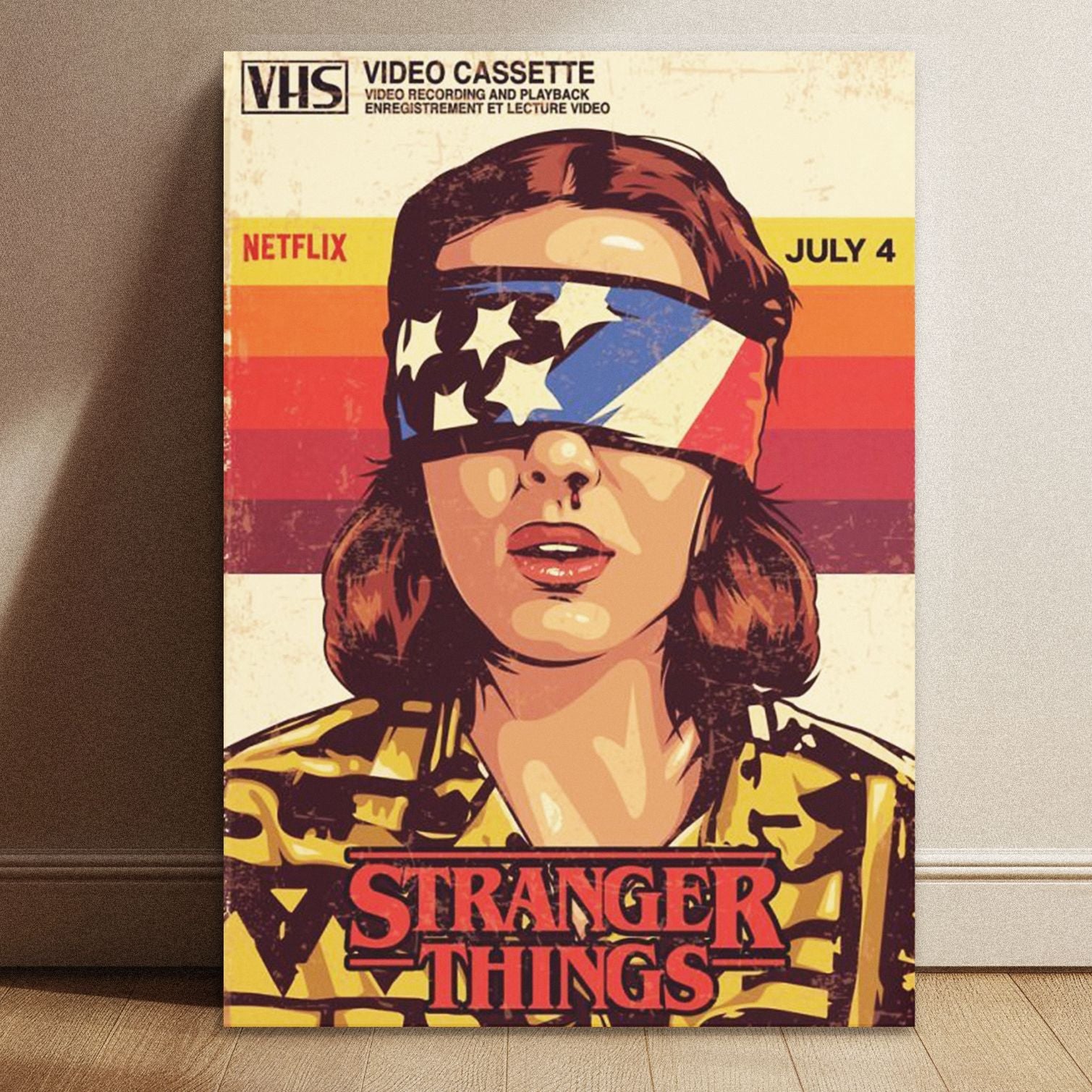 A hand holding up a retro Stranger Things July 4 Netflix poster featuring Eleven against a blurred textured white background.